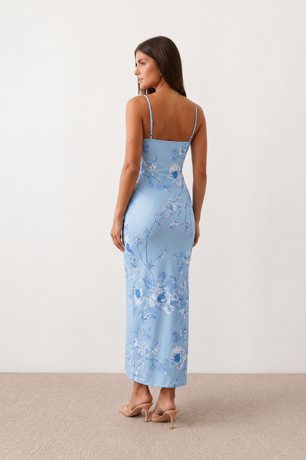 Woman wearing the Milota glossy floral slip maxi dress featuring a baroque-inspired floral print, deep V-neckline, adjustable spaghetti straps, low draped back, satin-look finish, and body-skimming floor-length silhouette, ideal for wedding guests and formal occasions.