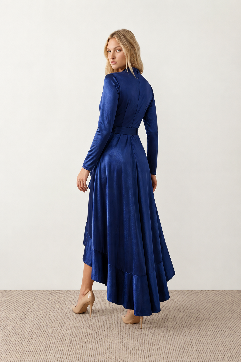 Woman wearing the Cordula Glossy Ruffle Detail Maxi Dress in a satin-look finish featuring a wrap V-neckline, long sleeves, self-tie waist sash and cascading asymmetric ruffle high-low hem, styled as an elegant wedding guest and occasion dress.