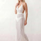 Woman wearing the white crochet halter neck backless maxi dress featuring an open-knit design, deep V-neckline, side cut-outs, elasticated waist, and full-length silhouette, styled as a lightweight beach holiday cover-up.