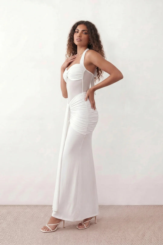 Woman wearing the Halter Neck Mermaid Maxi Dress featuring a sweetheart twist-knot neckline, sheer mesh waist panel, ruched mermaid silhouette, draped front skirt, open back with halter tie fastening, and elegant floor-length finish.