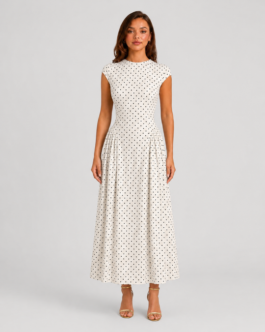 Woman wearing a polka dot maxi dress with a fitted bodice, cap sleeves, high neckline, and flowing pleated A-line skirt for elegant occasion wear.