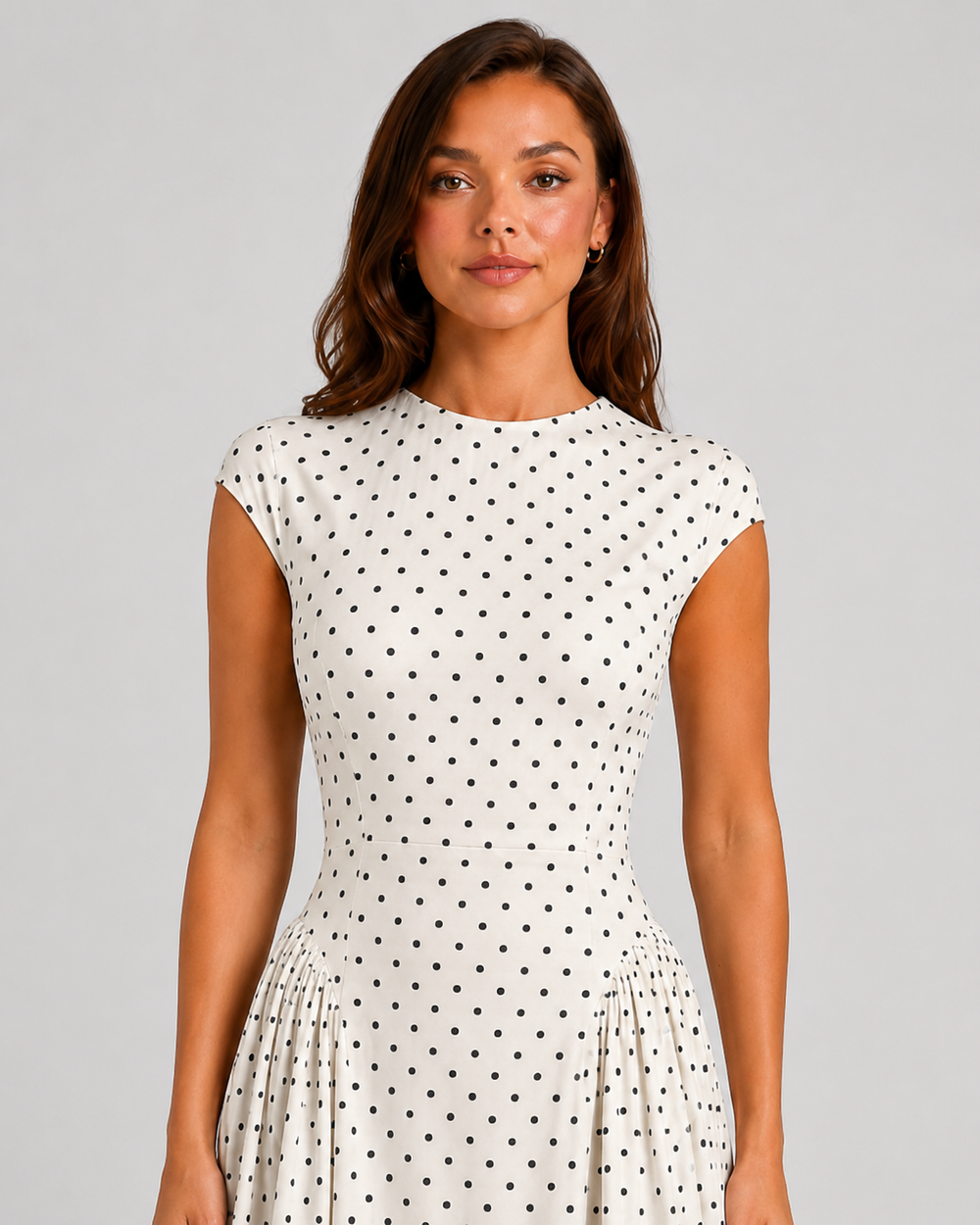 Woman wearing a polka dot maxi dress with a fitted bodice, cap sleeves, high neckline, and flowing pleated A-line skirt for elegant occasion wear.
