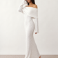 Woman wearing the Iustina Off Shoulder Fitted Maxi Dress featuring a Bardot neckline, soft draped shoulders, full-length sleeves, textured stretch knit fabric and a fitted floor-length silhouette, ideal for formal occasions and evening events.