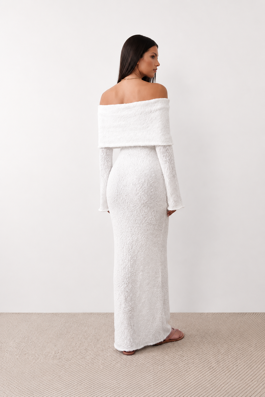 Woman wearing the Iustina Off Shoulder Fitted Maxi Dress featuring a Bardot neckline, soft draped shoulders, full-length sleeves, textured stretch knit fabric and a fitted floor-length silhouette, ideal for formal occasions and evening events.