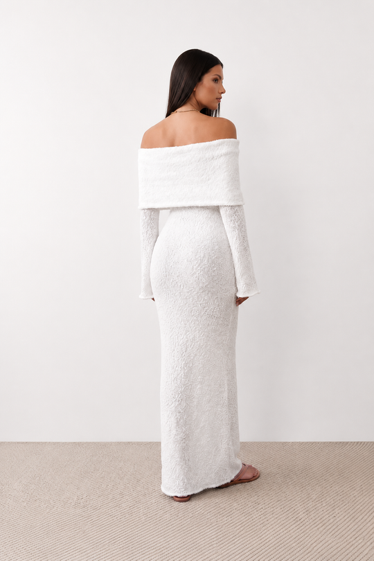 Woman wearing the Iustina Off Shoulder Fitted Maxi Dress featuring a Bardot neckline, soft draped shoulders, full-length sleeves, textured stretch knit fabric and a fitted floor-length silhouette, ideal for formal occasions and evening events.