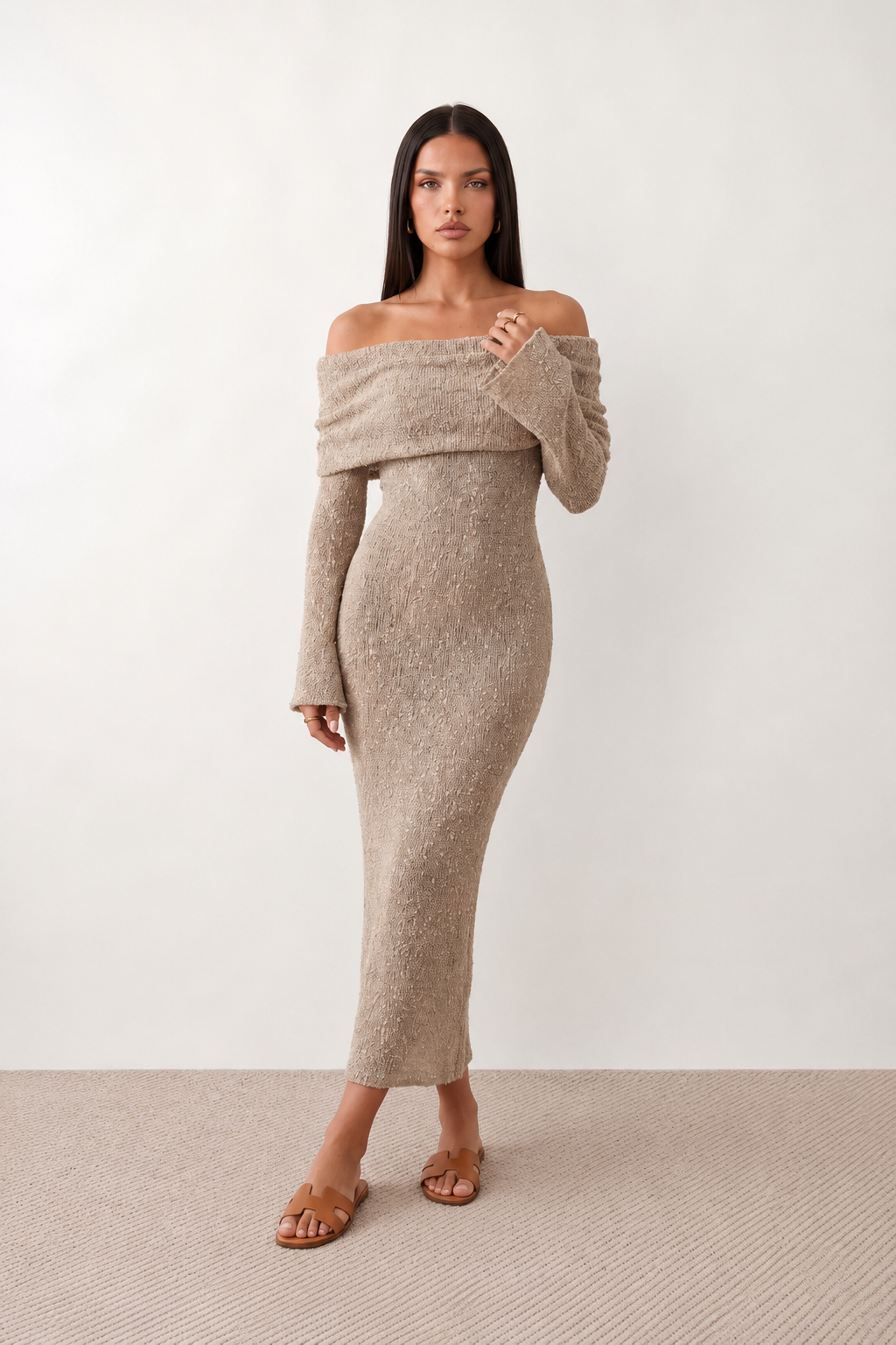 Woman wearing the Iustina Off Shoulder Fitted Maxi Dress featuring a Bardot neckline, soft draped shoulders, full-length sleeves, textured stretch knit fabric and a fitted floor-length silhouette, ideal for formal occasions and evening events.