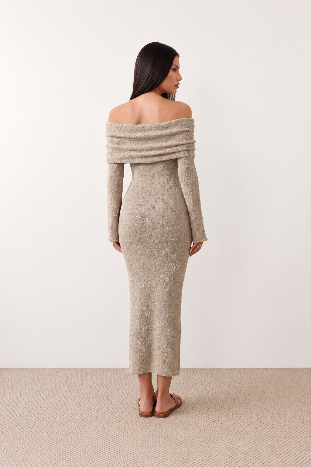 Woman wearing the Iustina Off Shoulder Fitted Maxi Dress featuring a Bardot neckline, soft draped shoulders, full-length sleeves, textured stretch knit fabric and a fitted floor-length silhouette, ideal for formal occasions and evening events.