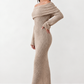 Woman wearing the Iustina Off Shoulder Fitted Maxi Dress featuring a Bardot neckline, soft draped shoulders, full-length sleeves, textured stretch knit fabric and a fitted floor-length silhouette, ideal for formal occasions and evening events.