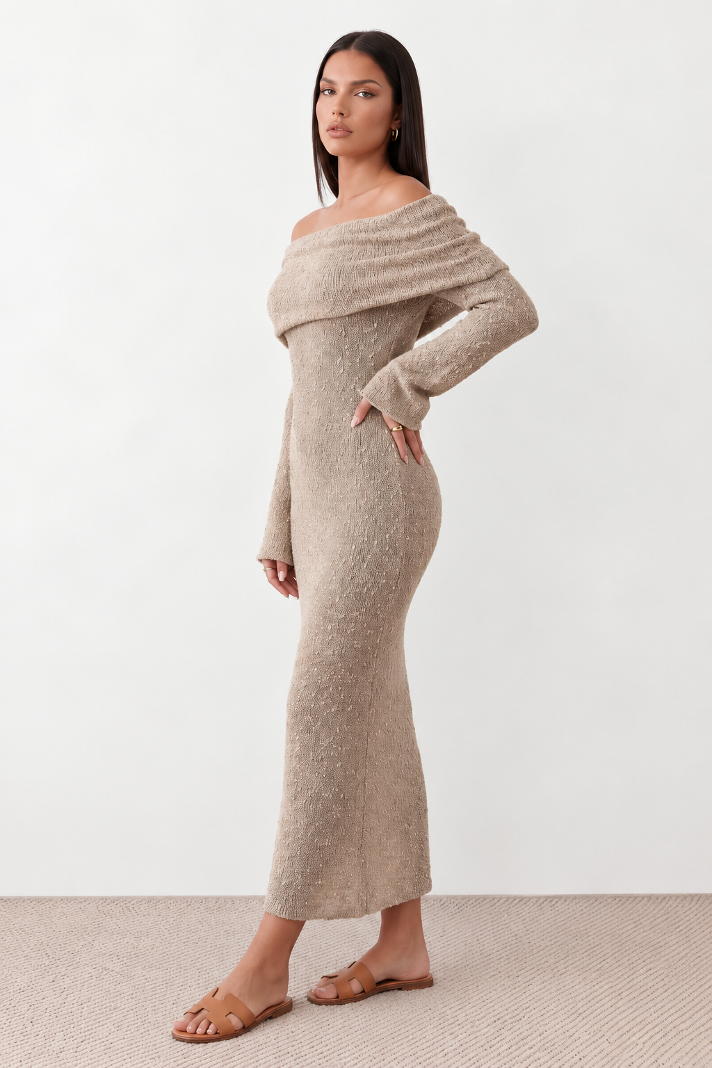 Woman wearing the Iustina Off Shoulder Fitted Maxi Dress featuring a Bardot neckline, soft draped shoulders, full-length sleeves, textured stretch knit fabric and a fitted floor-length silhouette, ideal for formal occasions and evening events.