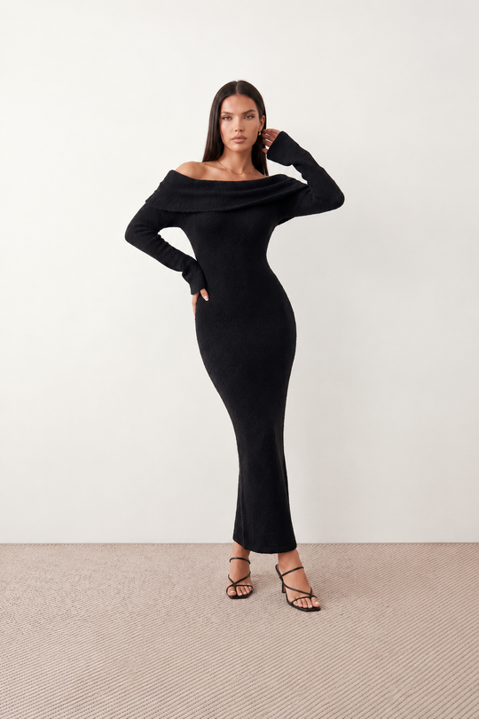 Woman wearing the Iustina Off Shoulder Fitted Maxi Dress featuring a Bardot neckline, soft draped shoulders, full-length sleeves, textured stretch knit fabric and a fitted floor-length silhouette, ideal for formal occasions and evening events.