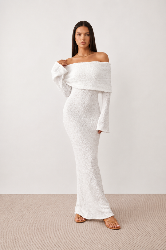 Woman wearing the Iustina Off Shoulder Fitted Maxi Dress featuring a Bardot neckline, soft draped shoulders, full-length sleeves, textured stretch knit fabric and a fitted floor-length silhouette, ideal for formal occasions and evening events.