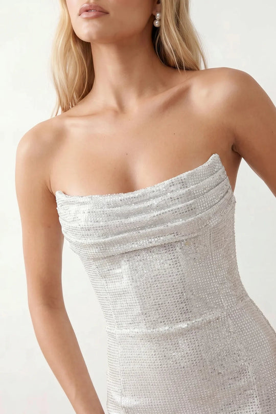 Woman wearing the Izabela sequined strapless maxi dress featuring shimmering all-over sequins, sparkling rhinestone embellishments, a ruched cowl-fold bust, adjustable lace-up corset back and a figure-skimming column silhouette with a floor-length hem, perfect for formal evening occasions.