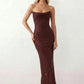 Woman wearing the Izabela sequined strapless maxi dress featuring shimmering all-over sequins, sparkling rhinestone embellishments, a ruched cowl-fold bust, adjustable lace-up corset back and a figure-skimming column silhouette with a floor-length hem, perfect for formal evening occasions.
