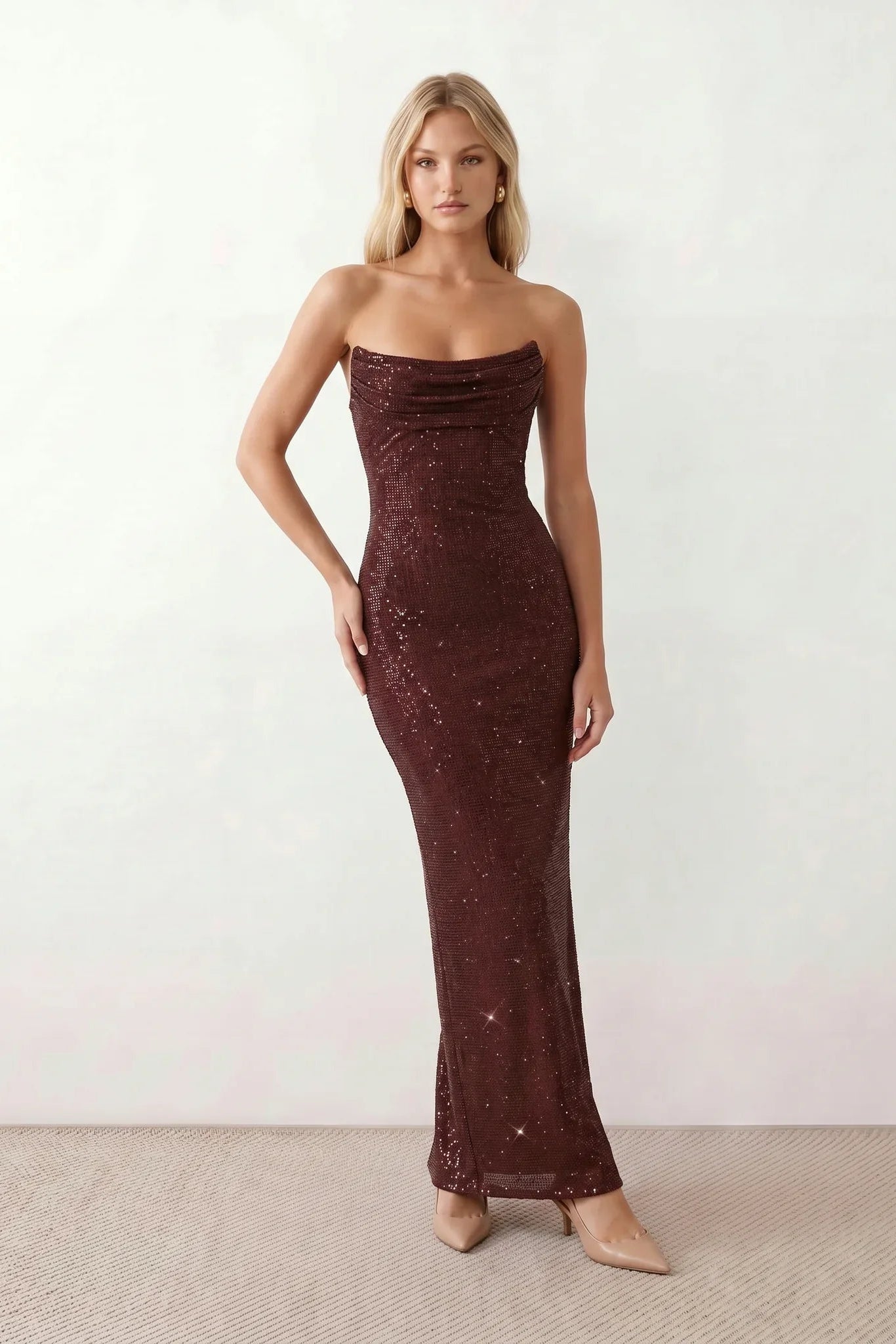 Woman wearing the Izabela sequined strapless maxi dress featuring shimmering all-over sequins, sparkling rhinestone embellishments, a ruched cowl-fold bust, adjustable lace-up corset back and a figure-skimming column silhouette with a floor-length hem, perfect for formal evening occasions.