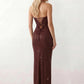Woman wearing the Izabela sequined strapless maxi dress featuring shimmering all-over sequins, sparkling rhinestone embellishments, a ruched cowl-fold bust, adjustable lace-up corset back and a figure-skimming column silhouette with a floor-length hem, perfect for formal evening occasions.