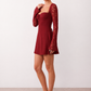 Woman wearing the Joaquina Lace Sweetheart Mini Dress in delicate lace-look fabric with a sweetheart neckline, long sleeves, an open lace-up back with bow detail, a defined waist and a flattering mini-length silhouette.