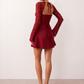 Woman wearing the Joaquina Lace Sweetheart Mini Dress in delicate lace-look fabric with a sweetheart neckline, long sleeves, an open lace-up back with bow detail, a defined waist and a flattering mini-length silhouette.