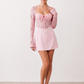 Woman wearing the Joaquina Lace Sweetheart Mini Dress in delicate lace-look fabric with a sweetheart neckline, long sleeves, an open lace-up back with bow detail, a defined waist and a flattering mini-length silhouette.