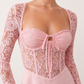 Woman wearing the Joaquina Lace Sweetheart Mini Dress in delicate lace-look fabric with a sweetheart neckline, long sleeves, an open lace-up back with bow detail, a defined waist and a flattering mini-length silhouette.