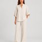 Woman wearing a neutral linen blend two-piece set featuring a button-up shirt and relaxed wide-leg trousers, styled for effortless warm-weather elegance.
