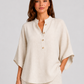 Woman wearing a neutral linen blend two-piece set featuring a button-up shirt and relaxed wide-leg trousers, styled for effortless warm-weather elegance.