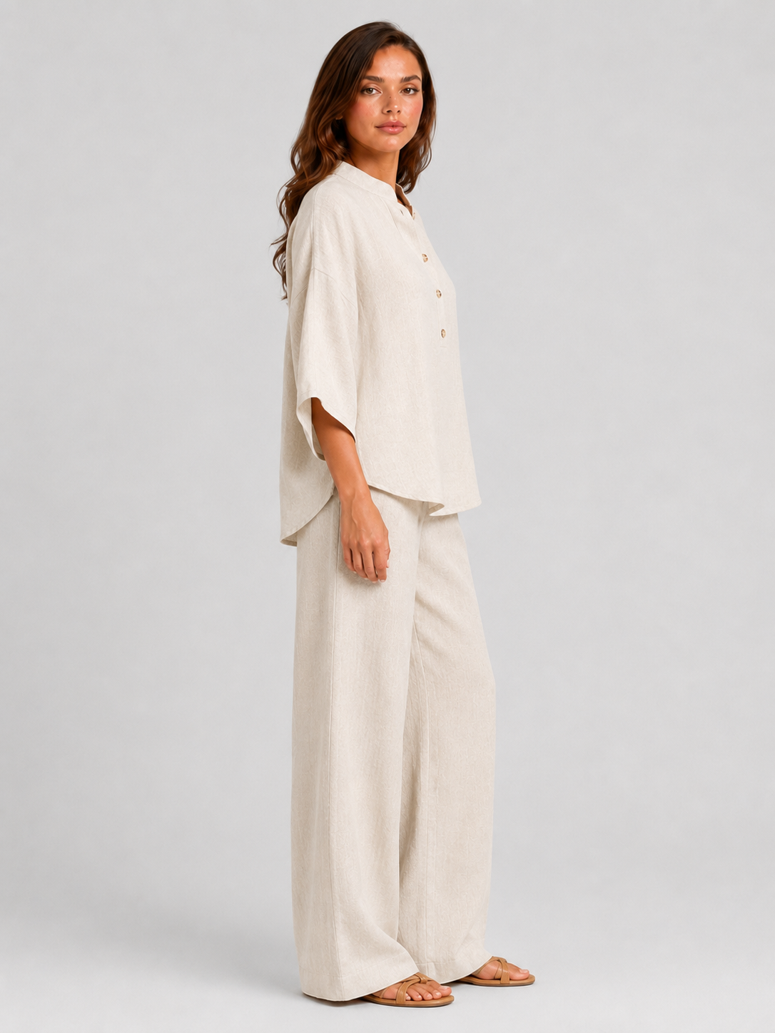 Woman wearing a neutral linen blend two-piece set featuring a button-up shirt and relaxed wide-leg trousers, styled for effortless warm-weather elegance.