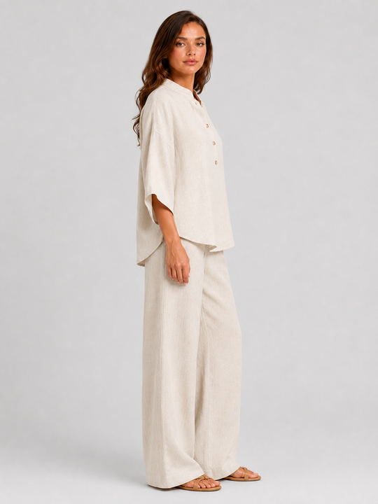 Woman wearing a neutral linen blend two-piece set featuring a button-up shirt and relaxed wide-leg trousers, styled for effortless warm-weather elegance.