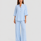 Woman wearing a neutral linen blend two-piece set featuring a button-up shirt and relaxed wide-leg trousers, styled for effortless warm-weather elegance.