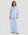 Woman wearing a neutral linen blend two-piece set featuring a button-up shirt and relaxed wide-leg trousers, styled for effortless warm-weather elegance.