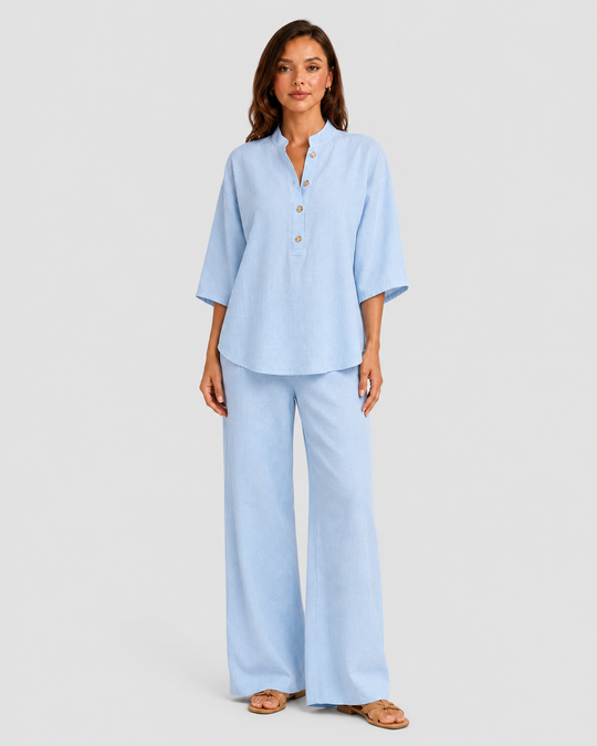 Woman wearing a neutral linen blend two-piece set featuring a button-up shirt and relaxed wide-leg trousers, styled for effortless warm-weather elegance.