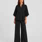 Woman wearing a neutral linen blend two-piece set featuring a button-up shirt and relaxed wide-leg trousers, styled for effortless warm-weather elegance.