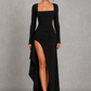 Women’s long sleeve stretch crepe maxi dress featuring a pleated waist, flared cuffs, fitted silhouette, and draped thigh-high split for evening and formal occasions.