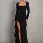 Women’s long sleeve stretch crepe maxi dress featuring a pleated waist, flared cuffs, fitted silhouette, and draped thigh-high split for evening and formal occasions.