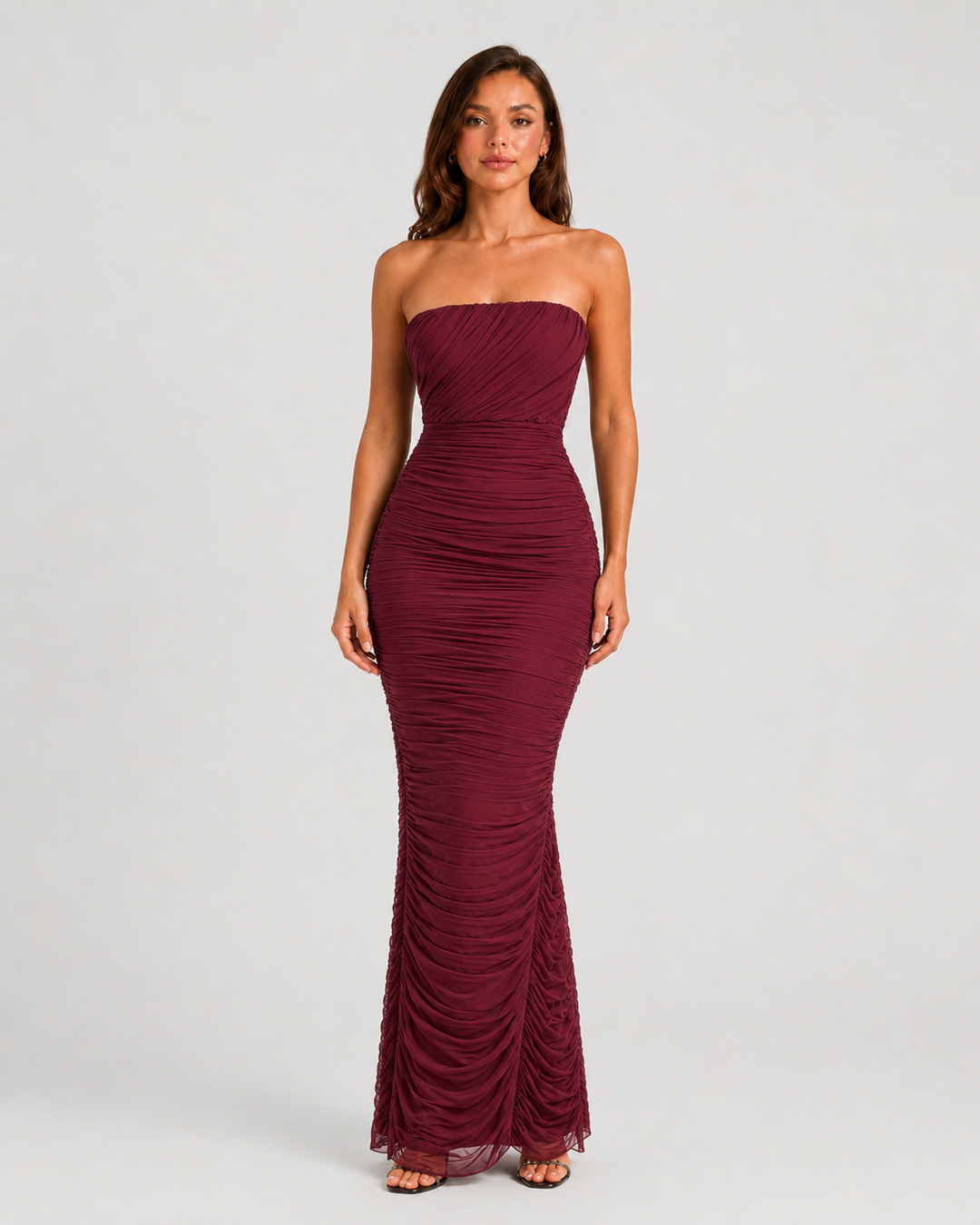 Woman wearing a strapless mesh maxi dress with internal corset detailing, elegant ruching, and a figure-hugging silhouette designed for formal evening occasions.