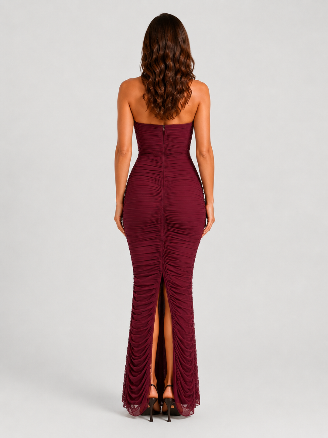 Woman wearing a strapless mesh maxi dress with internal corset detailing, elegant ruching, and a figure-hugging silhouette designed for formal evening occasions.