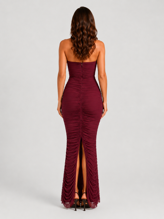 Woman wearing a strapless mesh maxi dress with internal corset detailing, elegant ruching, and a figure-hugging silhouette designed for formal evening occasions.