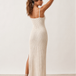 Woman wearing the Flora openwork spaghetti strap maxi dress in a pointelle knit with a V-neckline, adjustable straps, low back, and side slit for an elegant, airy silhouette.