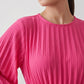 Woman wearing the Pleated Ruffle Detail Mini Dress featuring an all-over pleated design, flowing bell sleeves, a round neckline, elasticated waist with a self-tie sash, and a feminine ruffle hem, perfect for weddings, garden parties, race days, and elegant occasions.