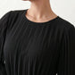 Woman wearing the Pleated Ruffle Detail Mini Dress featuring an all-over pleated design, flowing bell sleeves, a round neckline, elasticated waist with a self-tie sash, and a feminine ruffle hem, perfect for weddings, garden parties, race days, and elegant occasions.