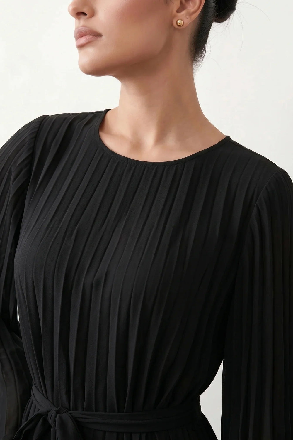 Woman wearing the Pleated Ruffle Detail Mini Dress featuring an all-over pleated design, flowing bell sleeves, a round neckline, elasticated waist with a self-tie sash, and a feminine ruffle hem, perfect for weddings, garden parties, race days, and elegant occasions.