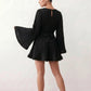 Woman wearing the Pleated Ruffle Detail Mini Dress featuring an all-over pleated design, flowing bell sleeves, a round neckline, elasticated waist with a self-tie sash, and a feminine ruffle hem, perfect for weddings, garden parties, race days, and elegant occasions.