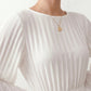 Woman wearing the Pleated Ruffle Detail Mini Dress featuring an all-over pleated design, flowing bell sleeves, a round neckline, elasticated waist with a self-tie sash, and a feminine ruffle hem, perfect for weddings, garden parties, race days, and elegant occasions.