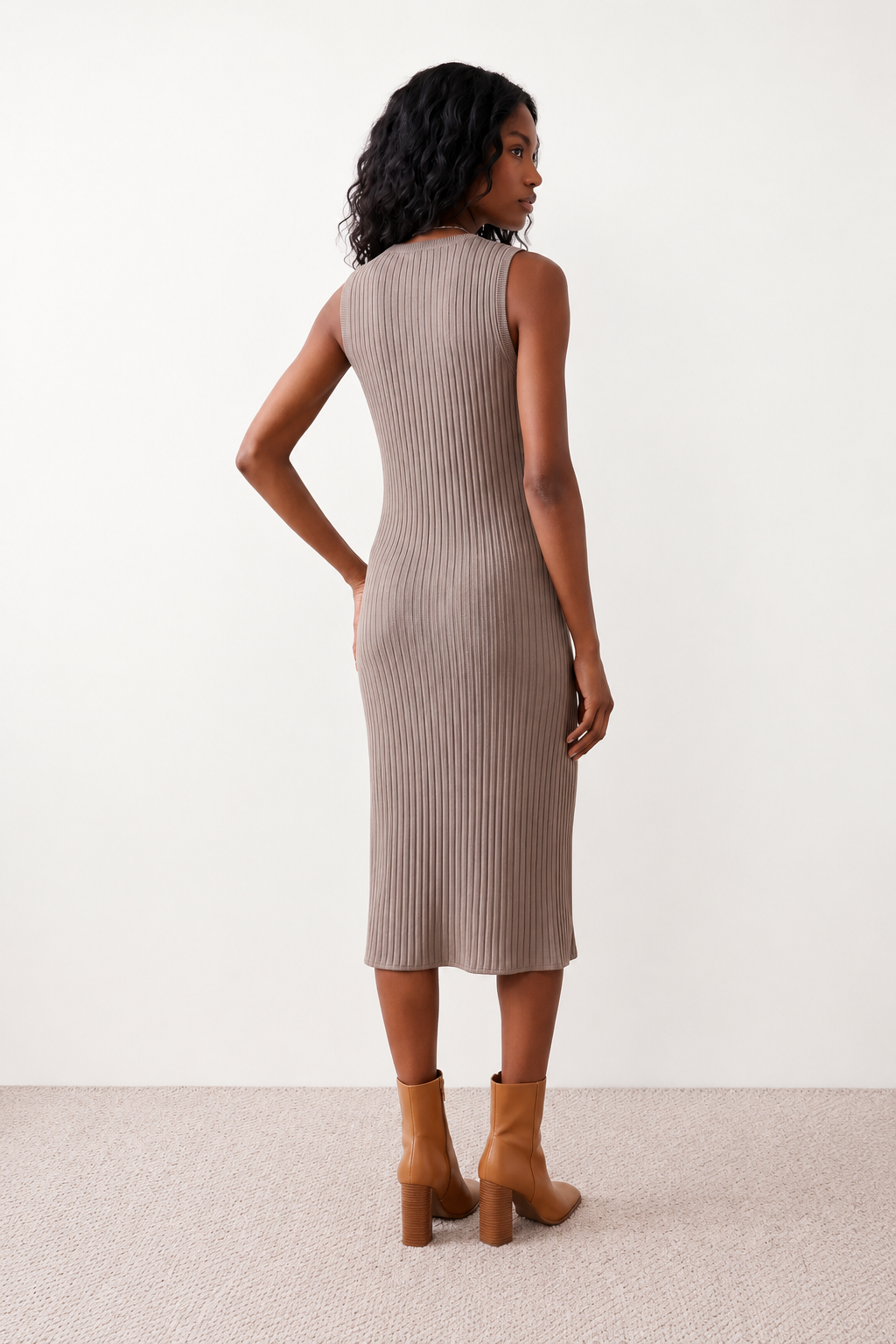 Woman wearing the Raina ribbed fitted midi dress in a sleeveless bodycon design with a round neckline, wide-rib knit texture and elegant side slit, styled as a sophisticated occasion dress.