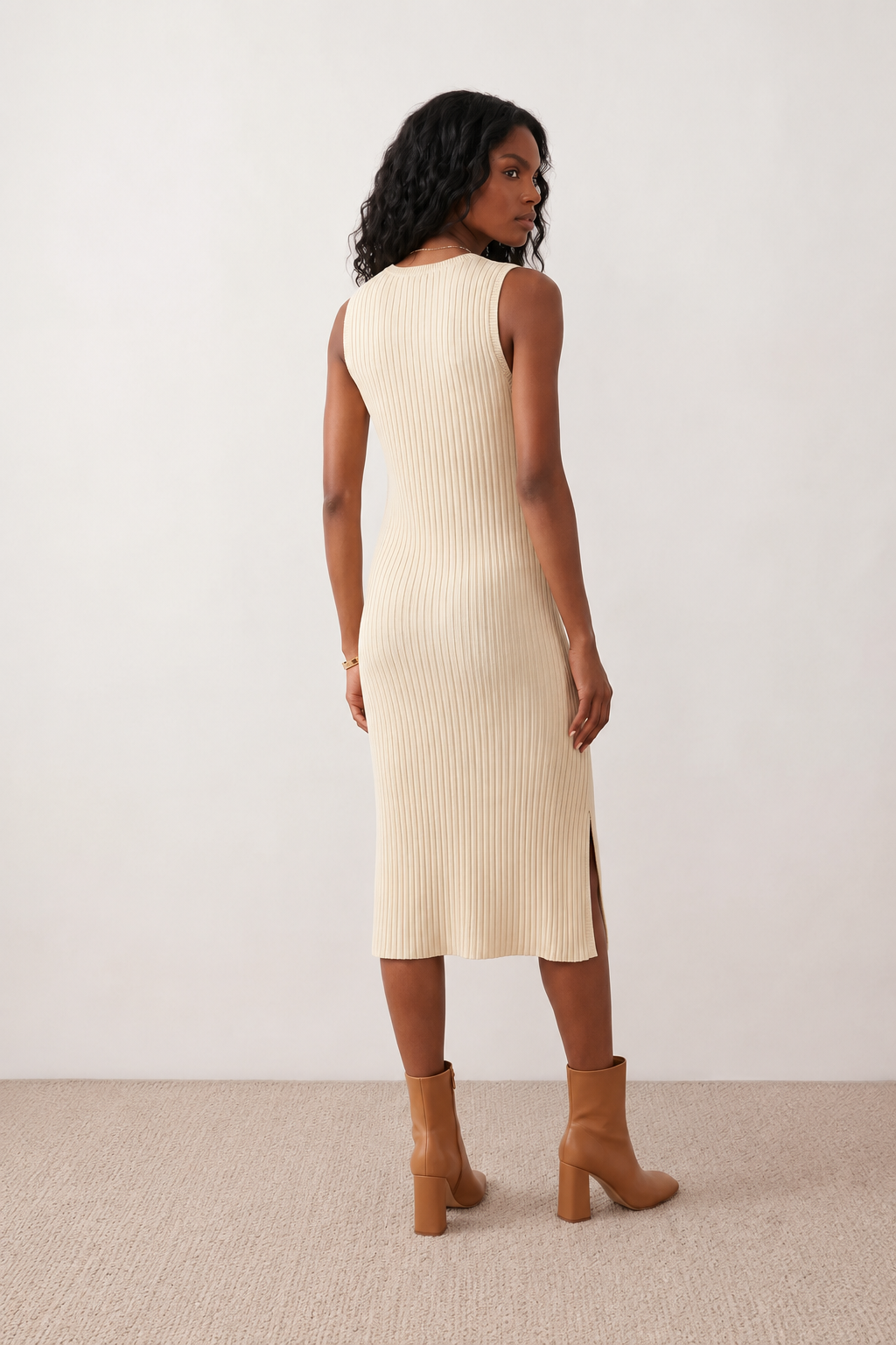 Woman wearing the Raina ribbed fitted midi dress in a sleeveless bodycon design with a round neckline, wide-rib knit texture and elegant side slit, styled as a sophisticated occasion dress.