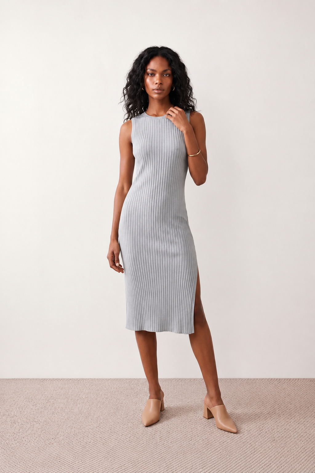 Woman wearing the Raina ribbed fitted midi dress in a sleeveless bodycon design with a round neckline, wide-rib knit texture and elegant side slit, styled as a sophisticated occasion dress.