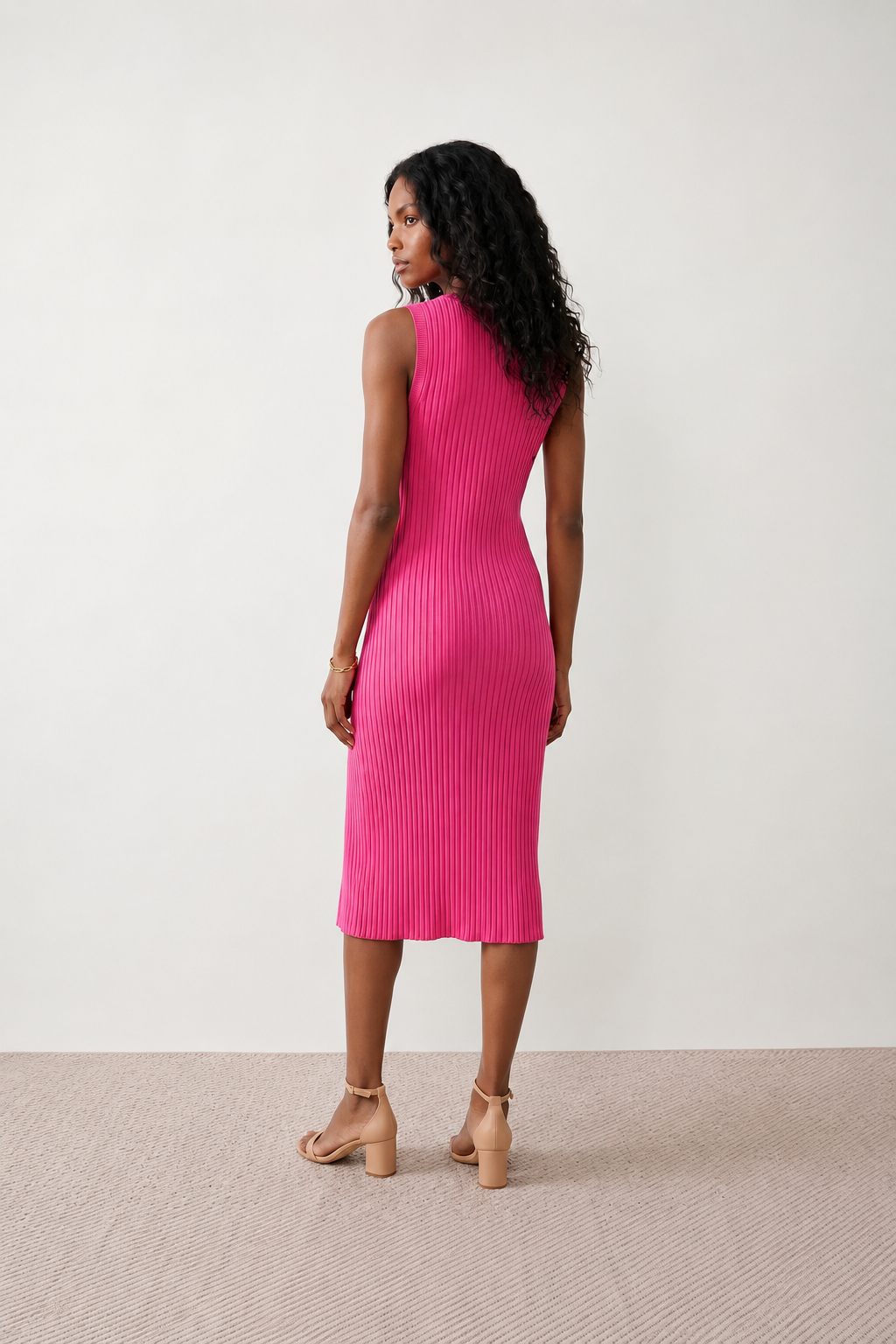 Woman wearing the Raina ribbed fitted midi dress in a sleeveless bodycon design with a round neckline, wide-rib knit texture and elegant side slit, styled as a sophisticated occasion dress.