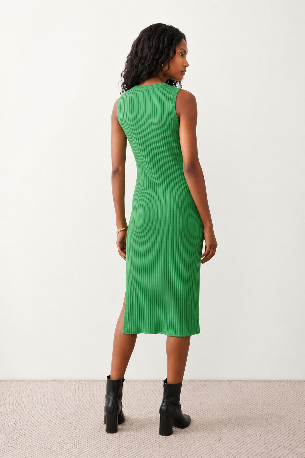 Woman wearing the Raina ribbed fitted midi dress in a sleeveless bodycon design with a round neckline, wide-rib knit texture and elegant side slit, styled as a sophisticated occasion dress.