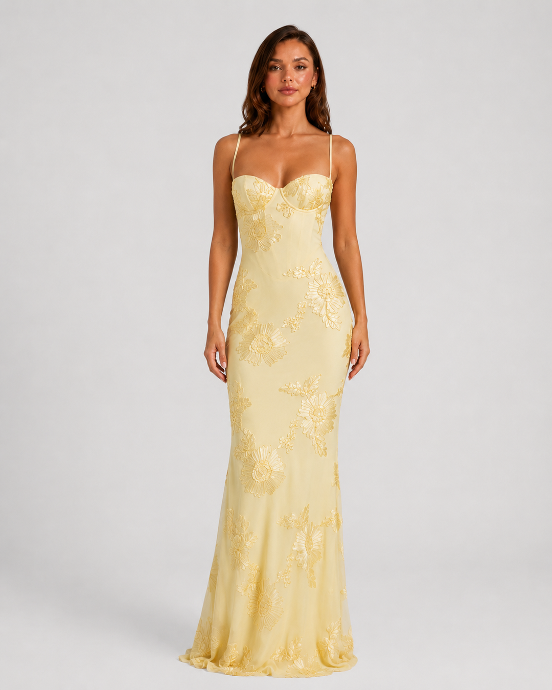 Woman wearing a floral embroidered corset maxi dress with delicate straps and a flowing full-length skirt, styled for weddings and formal occasions.