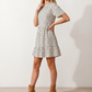 Women's Romy Polka Dot Ruffle Detail Mini Dress in lightweight woven chiffon featuring an all-over polka dot print, ruffled mock neckline, flutter sleeves, defined waist and tiered ruffle mini skirt, ideal for weddings, garden parties and elegant occasion wear.