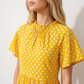 Women's Romy Polka Dot Ruffle Detail Mini Dress in lightweight woven chiffon featuring an all-over polka dot print, ruffled mock neckline, flutter sleeves, defined waist and tiered ruffle mini skirt, ideal for weddings, garden parties and elegant occasion wear.